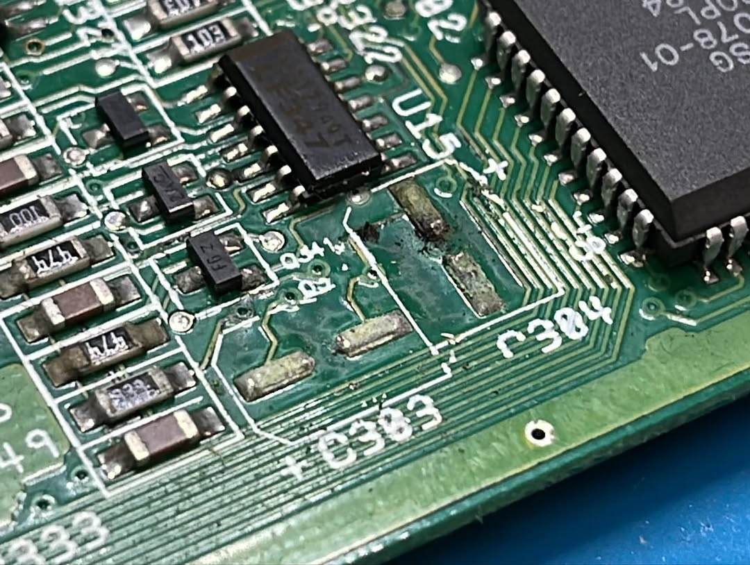Corrosione visibile sotto il chip U15 su scheda madre Amiga 600, causata da perdita di elettrolita